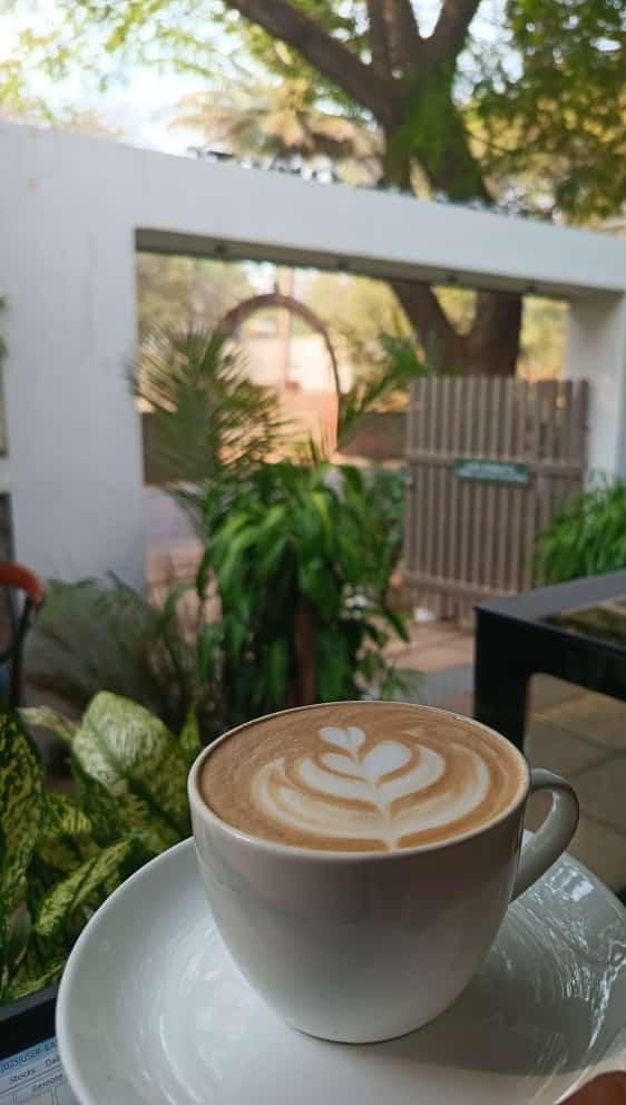 A latte at Cafe Robusta with the garden behind
